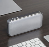 Portable speaker on a desk with a keyboard and laptop