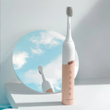Pink and white electric toothbrush with a mirror reflecting the sky in the background