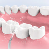Teeth being cleaned with a dental tool on a pink background