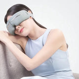 Woman wearing a gray eye mask on a plain background