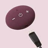 Purple electronic device with power symbol and USB cable on a pink background