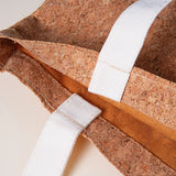 Close-up of a cork bag with white and orange straps on a light background
