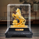 Gold horse statue in a clear glass case on a decorative stand with a blurred background