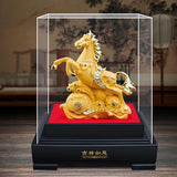 Gold horse figurine in a transparent display case on a wooden surface with a blurred background