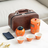 Tea set with orange teapot and cups, brown suitcase