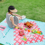 Turquoise and pink quilted 2-in-1 picnic mat bag unfolded on grass with picnic snacks_ corporate gift_customised gift singapore