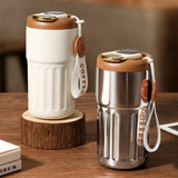 Cream and silver 450mlSmartTemperatureCoffeeTumbler with LED lids and leather straps on a wooden surface. Gift SHop