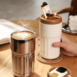 Cream and silver 450mlSmartTemperatureCoffeeTumbler with LED lids and leather straps on a wooden surface. Gift SHop