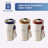 Cream and silver 450mlSmartTemperatureCoffeeTumbler with LED lids and leather straps on a wooden surface. Gift SHop