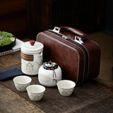 White teapot, tea can, three tea cups, packaged behind the shape of an artificial leather suitcase