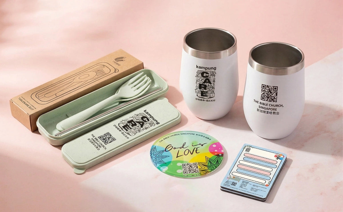 Set of stainless steel cups, a fork and knife set, and a coaster on a pink background