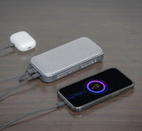 Portable power bank charging a smartphone and earbud