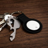 Black BrandCharger Bluetooth tracker in leather case with silver multi-tool on a dark wood surface_ customised Corporate Gifts