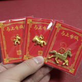 Three red envelopes with gold horse figurines held by a hand against a red background