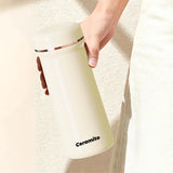Hand holding a cream-colored ceramic mug with 'Ceramito' branding on a light background