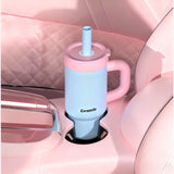 Pink and blue ceramic cup with straw in a car cup holder