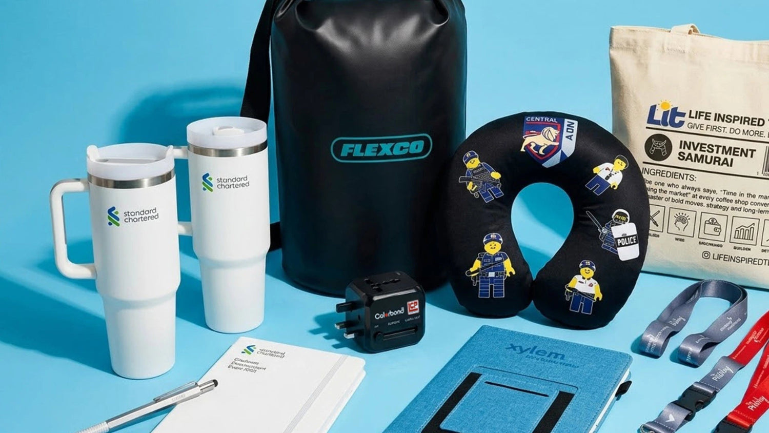 Collection of branded items including mugs, a bag, and a neck pillow on a blue background
