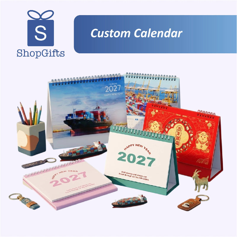 A promotional display of custom 2027 desk calendar products and matching keychains on a light lavender background. The collection includes various designs: a red Chinese New Year calendar with gold lion illustrations, a green and white New Year calendar, a blue cargo ship calendar, and other pink and multicolor options.