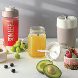 Thermos drink container with fruits and a smoothie on a white surface