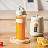 Thermos blender with orange juice on a wooden surface with lemons and a cherry.