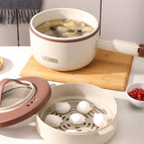 White thermos with brown lid containing soup, surrounded by a steamer basket with dumplings on a white surface.