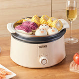 Thermos food steamer with vegetables on a wooden table next to a glass of wine.