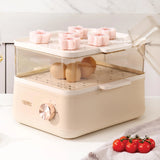 Beige food steamer with pink dumplings and tomatoes on a white surface
