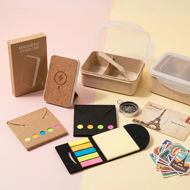 Collection of office supplies including a magnetic charger, cork block, and various stationery items on a pink background.