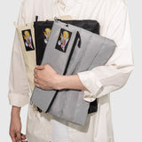 Person holding a stack of folded bags with embroidered designs on a white background