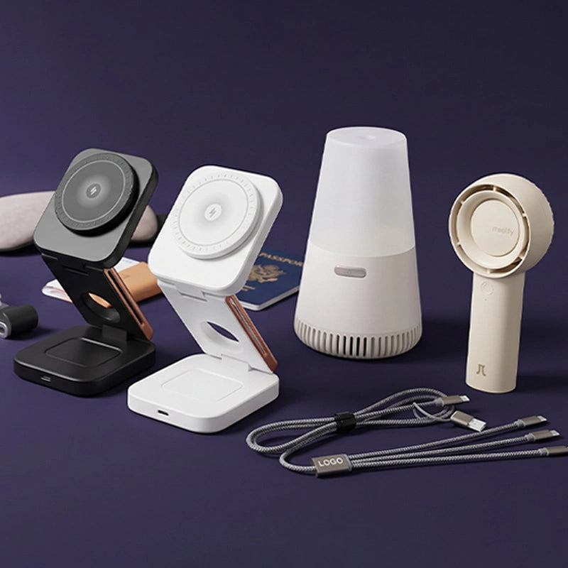 Collection of electronic devices including a phone stand, white device, white diffuser, beige handheld device, and cables on a dark background.