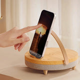 Hand using a wooden phone stand with a phone on it, against a neutral background