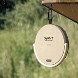 Beige portable speaker with 'Sport Singapore' branding hanging from an umbrella in a rain-soaked setting.