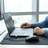 Logitech B100 corded USB mouse being used on a gray felt desk mat next to a laptop, a reliable tech essential for corporate gifting._customised corporate gift singapore
