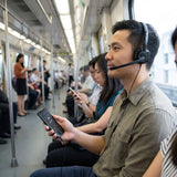 A commuter on a train listening to audio from a smartphone using the wired Logitech H151 headset, demonstrating its versatile, everyday portability._customised corporate gifts singapore