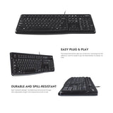 A remote professional using the full-size Logitech K120 wired keyboard on a wooden home office desk with an external monitor setup_Custom Keyboard Corporate gift