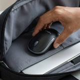 A hand retrieving a compact Logitech M185 wireless mouse from a padded laptop bag compartment, emphasizing travel-friendly corporate swag._customised Corporate gift Singapore
