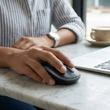 A user operating a black and gray Logitech M185 wireless mouse on a wooden desk next to a laptop with a plugged-in USB nano receiver_customised Corporate gift Singapore