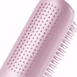 Pink hairbrush with textured handle on a white background