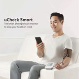 Person using a smart blood pressure monitor with uCheck Smart branding.