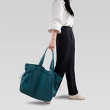 Person holding a teal bag on a plain background