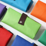 Vibrant green Premium Foldable Oxford Waterproof Tote Bag hanging on a wooden hook with folded color options_ customised corporate gift singapore