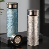Two Premium Titanium Thermos Bottle with metallic caps on a dark surface.