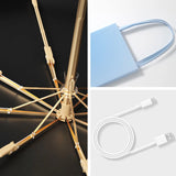 Gold umbrella with black background, blue bag with handle on white background, white cable and USB on white background