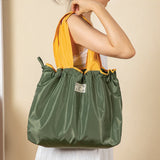 Green drawstring bag held by a person against a beige background