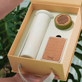 Tea-making set with a white cylindrical container, green lid, and brown base in an open beige box.