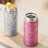 Two Titanium tumblers, one silver and one pink, on a light surface.