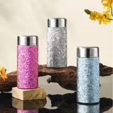 Three Titanium bottle in pink, silver, and blue on a wooden surface