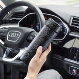 Person holding a Titanium hygienic thermal bottle in front of an Audi car dashboard