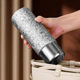 Person holding a Titanium Magnetic Infusion Mug over a beige handbag 