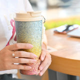 Person holding a gradient tumbler with a blurred background